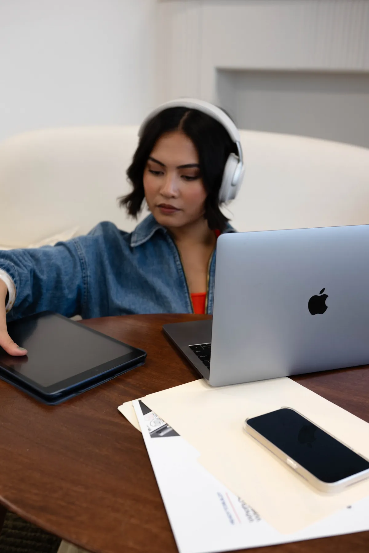 Gabby in headphones working on a laptop and tablet